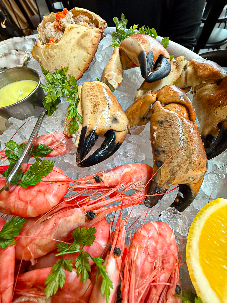 Fresh seafood platter with crab claws, shrimp, and shellfish served over ice at a restaurant in Stavanger, Norway.